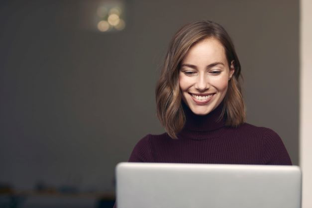 Attractive woman smiling as she interacts with a laptop